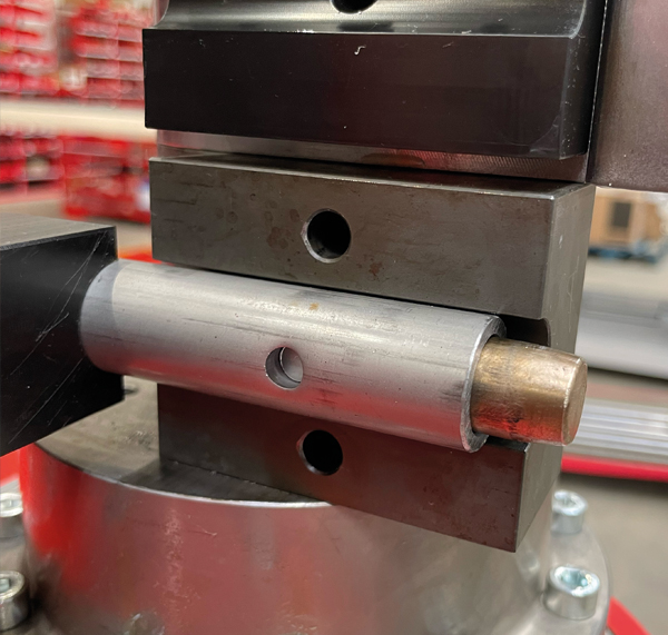 Stanzprozess an einem Metallrohr in einer automatisierten Rohrbearbeitungsmaschine.