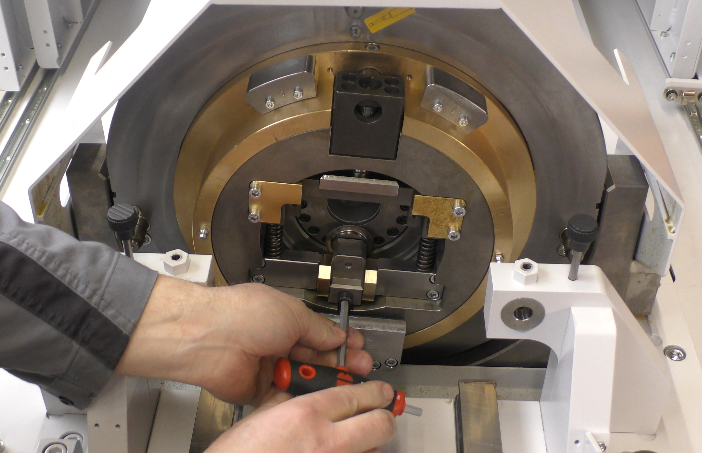 Werkzeugwechsel an einem orbitalen Trennkopf einer Rohrtrennmaschine, bei dem ein Bediener mit einem Schraubendreher Präzisionskomponenten justiert.