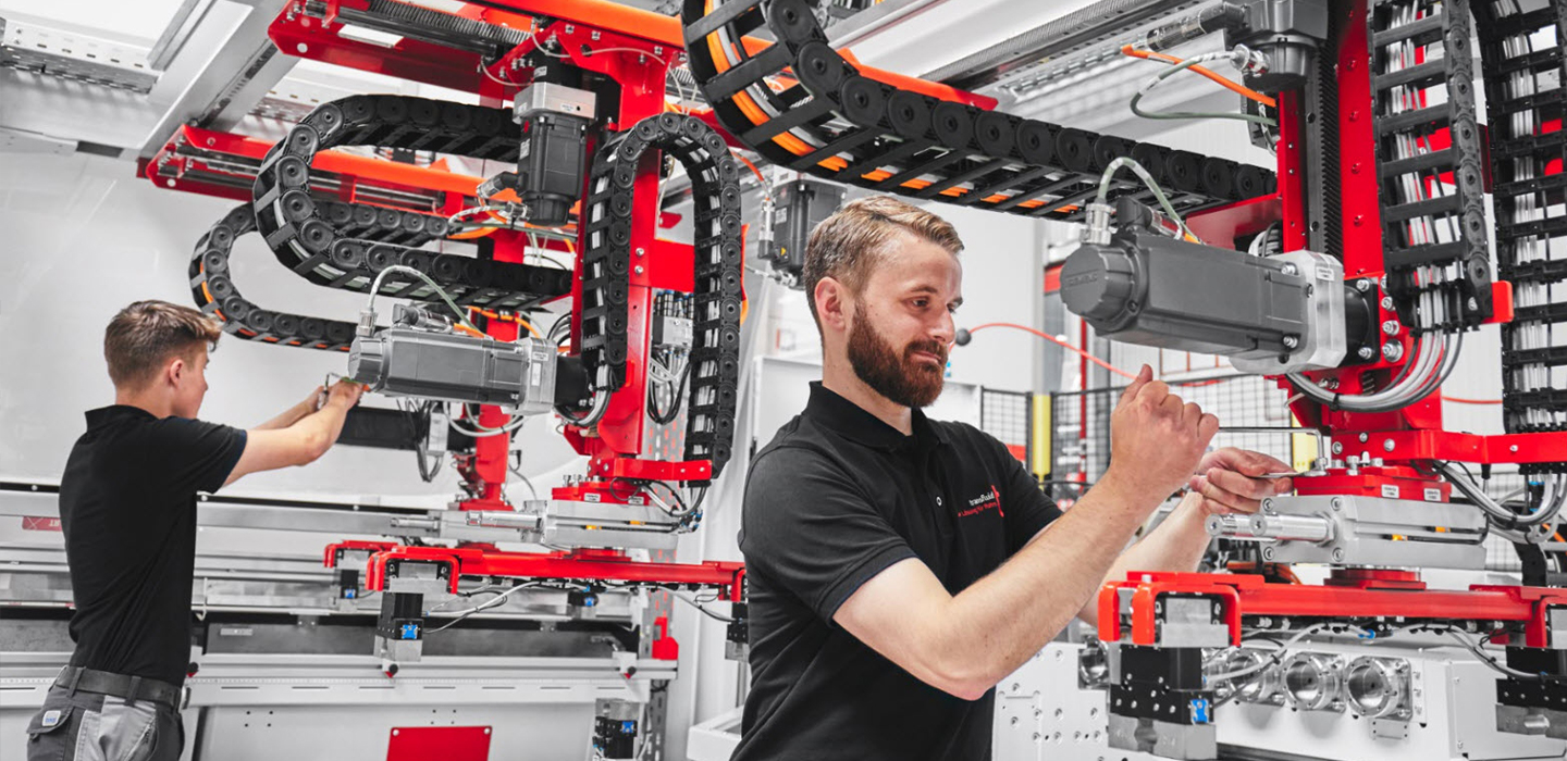 Mitarbeiter montieren Automationssysteme an transfluid Rohrbearbeitungsanlage in moderner Fertigung.