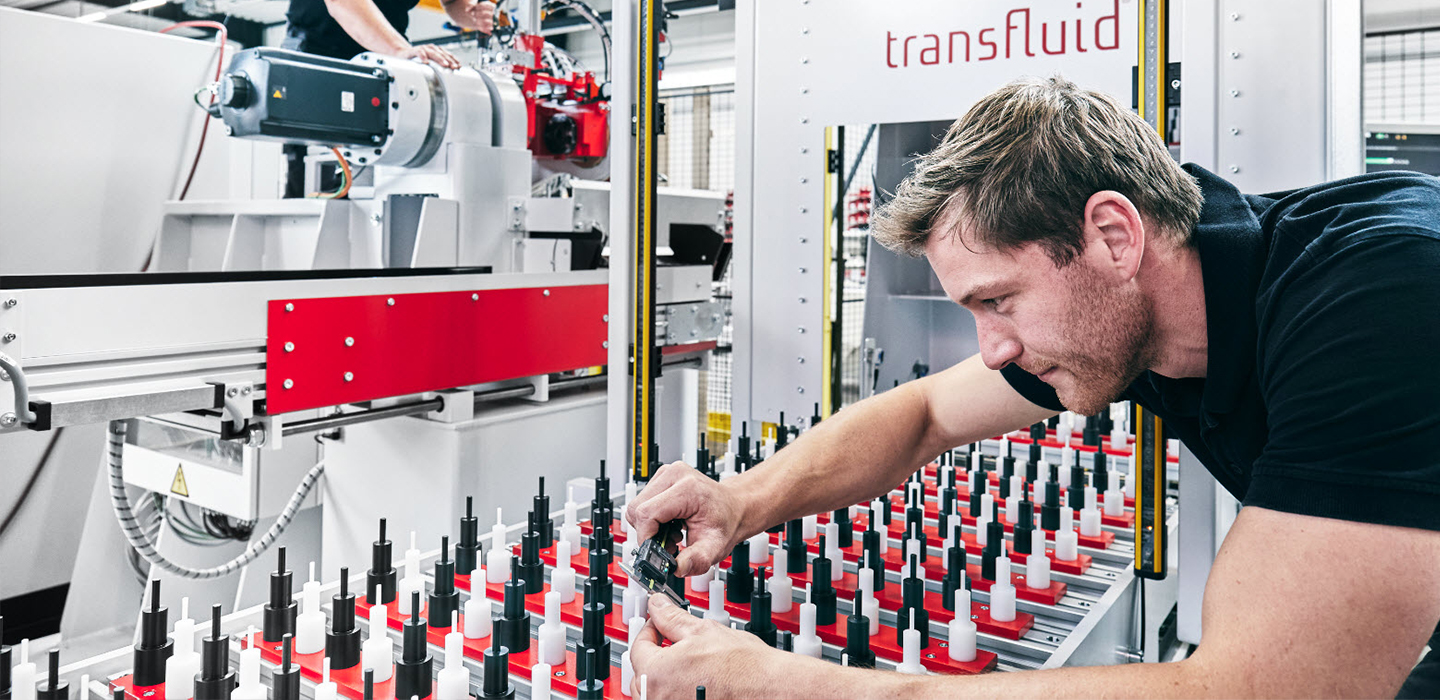 Mitarbeiter prüft Werkzeuge an automatisierter transfluid Rohrbearbeitungsanlage in Industrieumgebung.